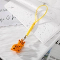 Ciondolo gatto 3D arancione con cordino giallo per cellulare e borse su sfondo di marmo - Gatto