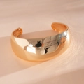 Macro view of a wide polished gold cuff bangle with smooth metallic finish - Bracelet - Silver