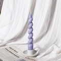 Elegant purple spiral soy wax candle on a white ceramic holder with soft fabric backdrop - Style A Purple