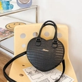 Borsa nera a forma di cuore con trama a coccodrillo e logo dorato su sedia gialla - Nero