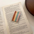Close-up of matte candy-colored metal hairpins set on a vintage book page backdrop - Arc