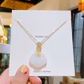 Collier en acier titane doré avec pendentif en jade blanc et détail nœud brillant - Boucle de Paix Nuage Blanche