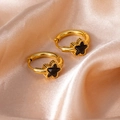 Detail of gold-plated hoop earrings with black star inlay on luxurious champagne silk fabric - Star Zircon / Black