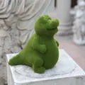 Flocced green dinosaur garden ornament with moss-like texture on a decorative stone - Crocodile
