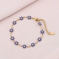 Detailed view of gold daisy chain bracelet with blue petals on a soft purple fabric - Blue (Gold)