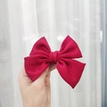 Elegant red satin bow hair clip with long ribbons shown in a handheld lifestyle view - Kids Duckbill Clip / Burgundy