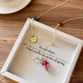 Detail of beaded necklace with red mushroom and green apple charms on a wood surface - Red Mushroom & Green Apple (6# Necklace-White)