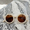 Flat lay of vintage round kids sunglasses with cream matte frames and brown lenses - White