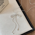 Detail of silver bow pendant necklace with dangling teardrop charms and sleek tassels - Silver