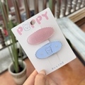 Primer plano de pinzas de resina rosa y azul con patrones de perros sobre cartón - Borde de Galleta - Pinzas de Pato Ovaladas Perro Pedrería (Set de 2)