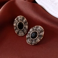 Macro detail of vintage gold oval earrings with black gemstones on red fabric - Silver Pin Black Gold