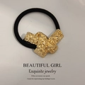 Minimalist elastic hair tie featuring a textured gold metal lava-style charm ornament - Embossed Surface Knotted Gold