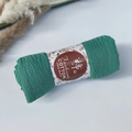 Detail of green pleated cotton scarf with floral band and handcrafted label on white table - Style #71