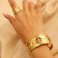 Dettaglio del set con anello dorato testurizzato e bracciale rigido su seta - Set Bracciale e Anello Traforato con Texture Geometrica