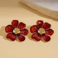 Dettaglio ravvicinato degli orecchini a fiore in smalto rosso con bordi dorati lucidi - Perno per orecchini in argento - Rosso
