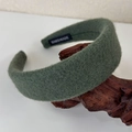 Detailed close-up of dark green wool headband featuring a white HANDMADE label on interior - Green