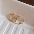 Primer plano macro de pendientes de aro de metal dorado trenzado sobre bandeja de papel - Dorado (1,4 cm de diámetro)