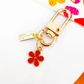 Golden metal keychain with a red enamel flower pendant and Hand Made engraved tag - Red