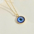 Macro shot of evil eye pendant with blue glass inlay on a gold chain necklace - Royal Blue Eye