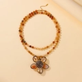 Macro shot of boho multilayer beaded necklace featuring a large amber glass flower pendant - Champagne