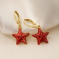 Detalle de pendientes de estrella de mar dorada con esmalte rojo sobre seda blanca - Rojo