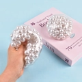 Gros plan d'une main pressant une balle anti-stress avec des perles blanches - Perle Blanche / 7cm