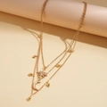 Detailed close-up of layered gold necklace featuring rhinestone star and moon pendants - Gold