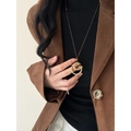 Gros plan d'un collier doré 24 carats porté avec une veste de costume marron élégante - Pendentif Rond Or