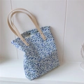 Detail der blauen Blumentasche mit beigen Ledergriffen und goldenen Nietendetails - Kleinblau Floral