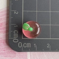 Makroaufnahme von 1,5cm rosa durchscheinendem Apfel-Anhänger aus Harz auf Skala - Mini 3D Transparenter Rosa Apfel