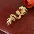 Prachtige vergulde draak broche met witte zirkonen op een rode lederen ondergrond - Goud