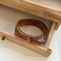 Amber tortoiseshell resin bangle with marble texture displayed on linen jewelry tray - Inner Diameter 66mm / Red Brown