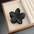 Elegant matte black flower hair claw clip with a five-petal design on a display tray - Matte Five-Petal Flower / Black