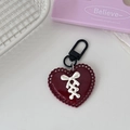 Deep red heart keychain with white ribbon bow and black metal clip on a white table - Red Heart