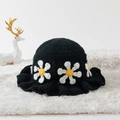 Close-up of handmade black crochet bucket hat with white daisy patterns on plush mat - One Size / White Daisy Black Base