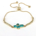 Detail of adjustable gold bead bracelet with blue crystal cross pendant on white background - Lake Blue