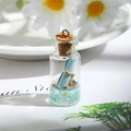 Macro detail of miniature glass drift bottle with tiny blue scroll and natural shells - Light Blue Drifting Bottle