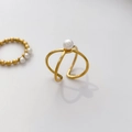 Close-up of golden cross-over open ring featuring a white freshwater pearl accent - US 6 / Cross Open Freshwater Pearl