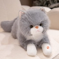 Peluche de chat gris et blanc avec fonction sonore posée sur un canapé douillet - Gris