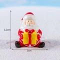 Vista macro di una statuina di Babbo Natale con scatola regalo e dimensioni di 3,2 cm - Babbo Natale con Scatola Regalo