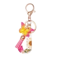 Macro detail of resin letter J keychain with real flowers, tassel, and butterfly - Flower Pattern J