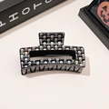 Detail of a black square hair claw clip featuring a holographic skull and crossbones print - Black Skull