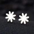 Macro shot of polished silver daisy flower stud earrings on black textured surface - Daisy / Silver