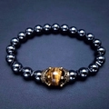 Dettaglio del bracciale con corona dorata, occhio di tigre e perle di ematite nera - Ematite Occhio di Tigre