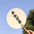 Chinese style hand fan with Ping An Xi Le calligraphy on off-white silk and tan handle - Peace and Joy
