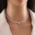 White beaded necklace with gold heart pendant and shell letter S charm on model - S
