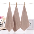 Three-piece light brown coral fleece face towels with scalloped edges hanging on a rope - 23x23cm / Brown