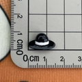 Close-up of a small black resin hat charm measured on a metric ruler for size clarity - Black White Hat Small