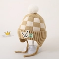 Detail van het bruine schaakbordpatroon en de pluche pompon op een wintermuts voor kinderen - Licht Kaki Schaakbord Beer Stijl / Lichtbeige