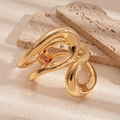 Makroaufnahme der goldenen Haarklammer im flüssigen Kurven-Design auf Naturstein - Gold